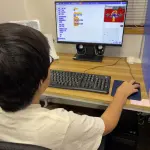 Scratchでプログラミングコンテストへの応募作品を最終調整する生徒の後ろ姿