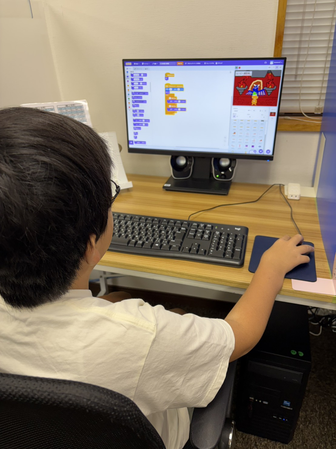 Scratchでプログラミングコンテストへの応募作品を最終調整する生徒の後ろ姿
